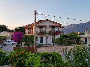 a white house with flowers in the front yard at Filippos Apartments "Room 6" in Spartià