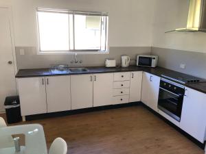 a kitchen with white cabinets and a sink and a window at Airlie Getaway Unit 1 in Cannonvale