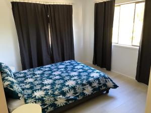 a bedroom with a bed with a blue and white blanket at Airlie Getaway Unit 1 in Cannonvale