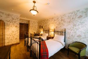 2 camas en una habitación con papel pintado floral en Rokeby Manor, en Invergarry