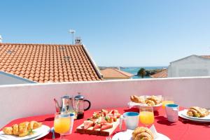 a table with plates of food and drinks on a balcony at Gem at The Beach in Vila Nova de Milfontes