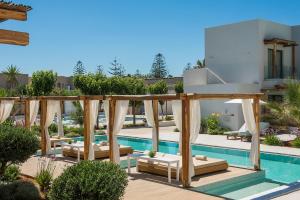 a swimming pool with chaise lounges next to a house at Paralos Lifestyle Beach Adults Only in Amoudara Herakliou