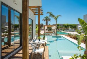 a swimming pool with a table and chairs next to a house at Paralos Lifestyle Beach Adults Only in Amoudara Herakliou