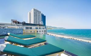 a pool with chaise lounge chairs and a beach at Santa Luxury Hotel in Da Nang