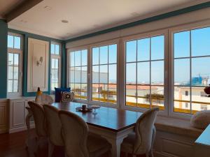 a dining room with a table and chairs and windows at Olive Tree in Tirana