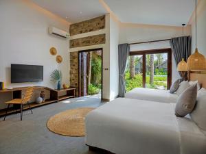 a bedroom with a bed and a desk and a television at M Village Phu Quoc in Phú Quốc