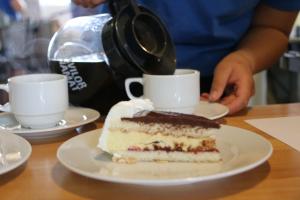 una persona está vertiendo café en un pedazo de pastel en Nissum Fjord Camping en Fjand Gårde