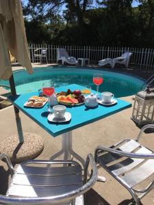 een tafel met eten en wijnglazen naast een zwembad bij Sandilos in Sorso