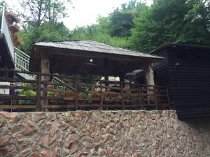 un pabellón de madera con flores en una pared de piedra en Etno House Stari mlin, en Konjic