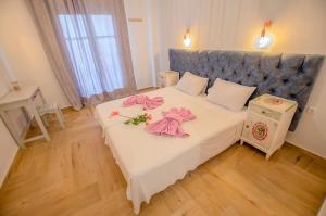 a bedroom with a bed with pink robes on it at Kapetanios Luxury in Agios Georgios