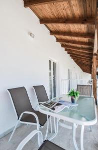 een glazen tafel en stoelen op een balkon bij Imeres Studios & Apartments in Polykhrono