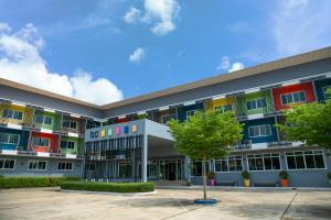 a building with colorful windows and a tree in the courtyard at Bun Hotel in Suratthani