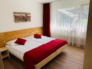 a bedroom with a bed with a red blanket and a window at Appartements Elan in Zermatt