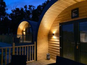 ein Holzhaus mit einer gewölbten Tür auf einer Terrasse in der Unterkunft Daviot Luxury Pods in Inverness