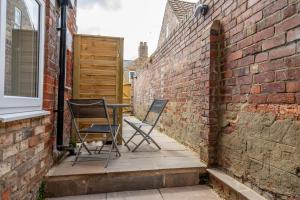 2 chaises et une table sur une terrasse à côté d'un mur de briques dans l'établissement Knavesmire Studio, à York
