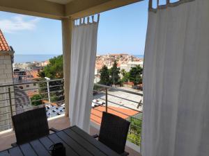 a balcony with a table and chairs and a large window at Apartments Romano in Dubrovnik