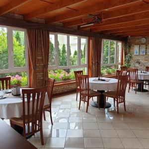 a dining room with tables and chairs and windows at Villa Dorottya in Balatonföldvár