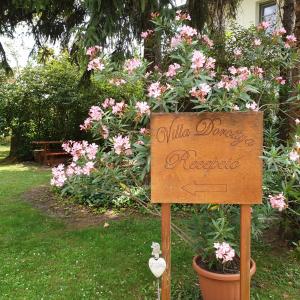 un cartel frente a un jardín con flores rosas en Villa Dorottya, en Balatonföldvár