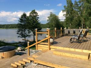 una terrazza in legno accanto a un lago con griglia di Hattapukki - Villa Himpula a Sysmä