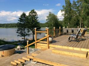 a wooden deck next to a lake with a grill at Hattapukki - Villa Himpula in Sysmä