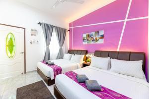 two beds in a room with a purple wall at Cenang Rooms With Pool by Virgo Star Resort in Pantai Cenang