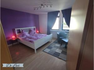 een slaapkamer met een wit bed en een paarse muur bij De Lux Gästehaus Völklingen in Völklingen