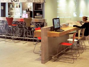 a woman sitting at a counter with a computer at ibis Paris Porte d'Italie in Gentilly