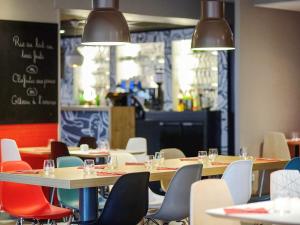 un comedor con mesas, sillas y luces en ibis Poitiers Beaulieu, en Poitiers