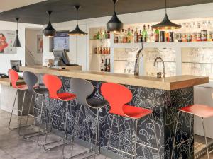 een bar met rode barkrukken in een restaurant bij ibis Chalons en Champagne in Châlons-en-Champagne