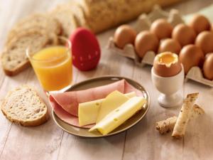 una mesa con un plato de queso, huevos y pan en ibis Abbeville, en Abbeville