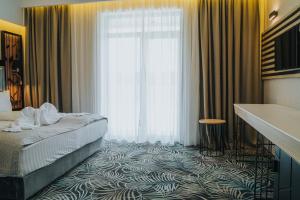 um quarto de hotel com uma cama e uma grande janela em Hotel President em Baile Felix