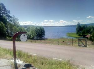 a road with a sign next to a body of water at Dimgården in Leksand