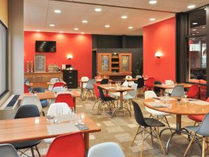 un ristorante con tavoli, sedie e pareti rosse di ibis Le Puy-en-Velay Centre a Le Puy en Velay