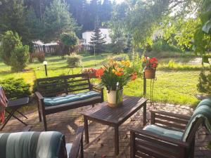 un patio con 2 bancos y una mesa con flores en Guest House Pechersky & Sons, en Dreiliņi