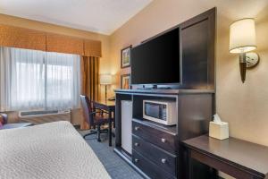a hotel room with a bed and a flat screen tv at Clarion Pointe Medford in Medford