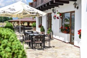 a restaurant with tables and umbrellas on a patio at Pensiunea Bergtal in Râşnov