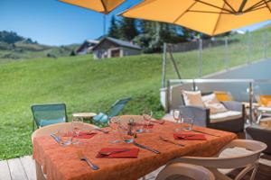 einen Holztisch mit Weingläsern auf einer Terrasse in der Unterkunft Hôtel Le Christania in Bellevaux