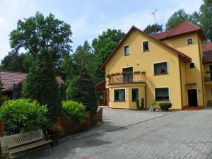 a yellow house with a bench in front of it at Dom Goscinny Andy in Pobierowo