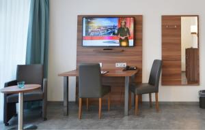 een eettafel met stoelen en een televisie aan de muur bij Neu Heidelberg - Guesthouse & Apartments in Heidelberg