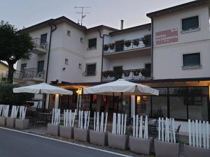 two white umbrellas and chairs in front of a building at Hotel La Favorita in Peschiera del Garda