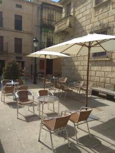 un gruppo di tavoli e sedie con ombrellone di Casa Turística Plaza del Conde a Ciudad-Rodrigo