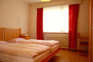 Duas camas num quarto com cortinas vermelhas e uma janela. em Skilifts & Central | Palma A em Crans-Montana