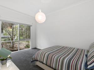 a white bedroom with a bed and a window at Niche On Noble in Anglesea