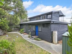 a grey house with a blue door and a yard at Niche On Noble in Anglesea