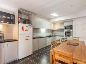 a kitchen with a wooden table and a white refrigerator at Oceans 12 in Anglesea