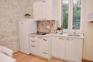 een witte keuken met een wastafel en een koelkast bij Step to Kotor bay Guesthouse in Kotor