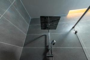 a shower in a bathroom with gray tiles at Fusionsea Villa in Vung Tau