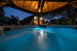 a swimming pool under a wooden roof at night at La Grange de Léonie Chambres d'hôtes Piscine et Spa Calme et à 5min A71 A20 A85 in Vierzon