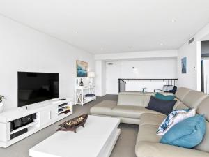 ein Wohnzimmer mit weißen Möbeln und einem Flachbild-TV in der Unterkunft Lorne Chalet Apartment 11 Odyssea in Lorne