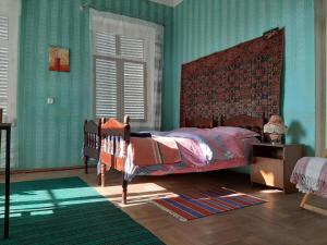 una camera da letto con pareti verdi e un letto con testiera rossa; di Cabernet Tali a Telavi